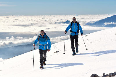 Full length of people on snow covered mountain against sky