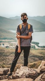 Man wearing sunglasses standing on rock