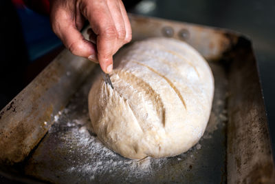 Unrecognizable chef cutting a bread in the kitchen.