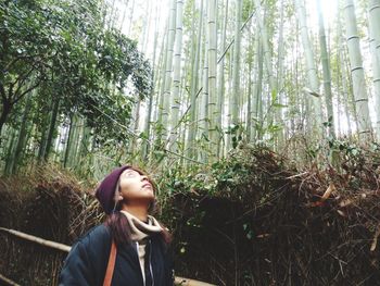 Female hiker looking up while standing in bamboo forest