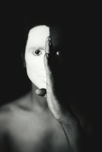 Close-up portrait of shirtless man with face paint against black background