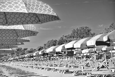 Deck chairs by parasols against sky