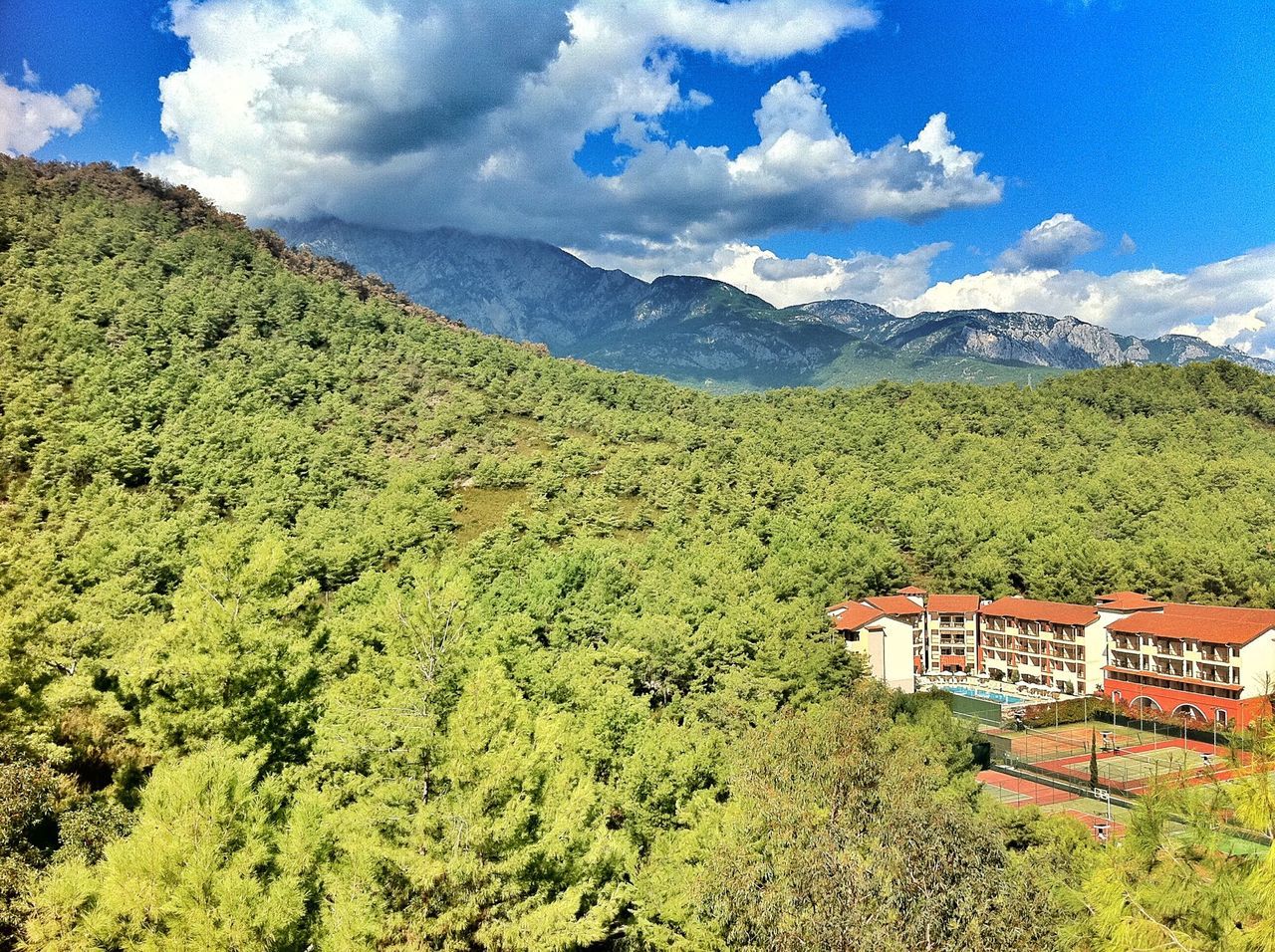 mountain, sky, tranquil scene, tree, tranquility, scenics, green color, landscape, beauty in nature, mountain range, nature, built structure, cloud - sky, cloud, architecture, lush foliage, house, growth, building exterior, idyllic