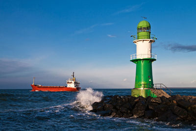 Lighthouse by sea against sky