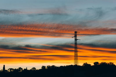 Low angle view of silhouette electricity pylon against sky during sunset