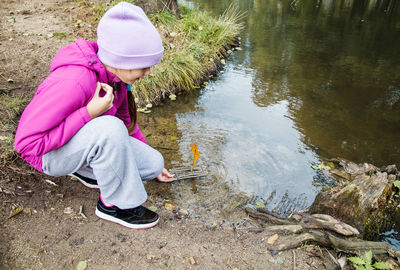 Girl crouching by pond