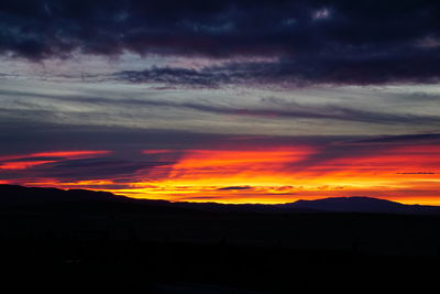 Silhouette landscape against dramatic sky during sunset
