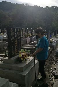 Man standing on cemetery against trees