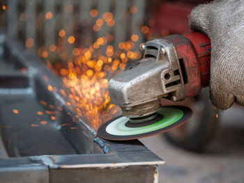 Low angle view of illuminated industry. worker grinding cutting metal sheet grinder machine welding 