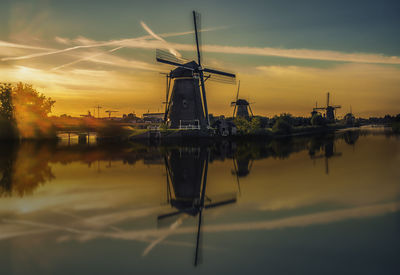 Traditional windmill against sky during sunset