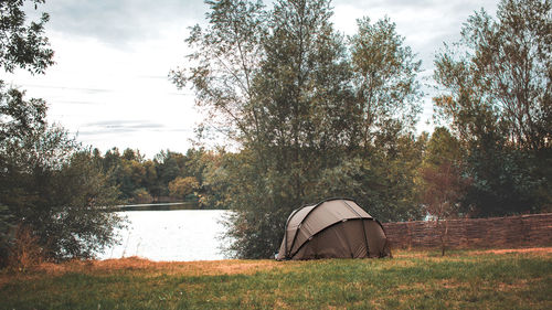 Tent on field by lake against sky