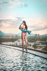 Full length of young woman standing in by pool