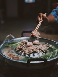 Close-up of hand holding food in chopsticks