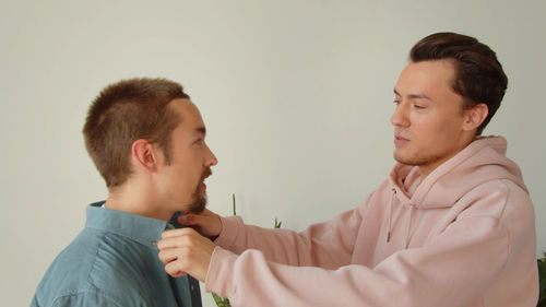 Smiling gay couple embracing at home