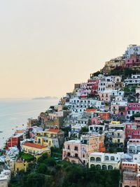 Buildings by sea against sky at sunset