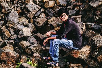 Young man sitting on rock