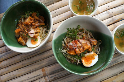 Dried noodles with crispy pork in a bowl placed on a bamboo table