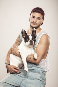 Portrait of young man with dog against white background