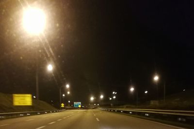 Empty road along illuminated street lights at night