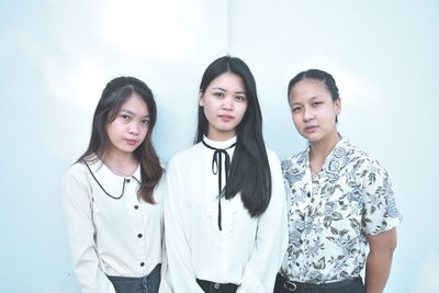 Portrait of young women standing against gray background