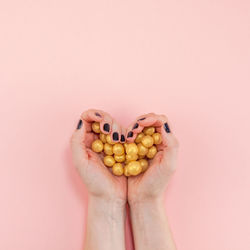 Close-up of hand holding tomato over white background