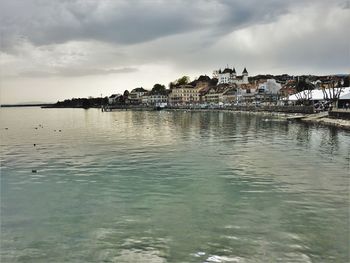 Buildings by sea against sky