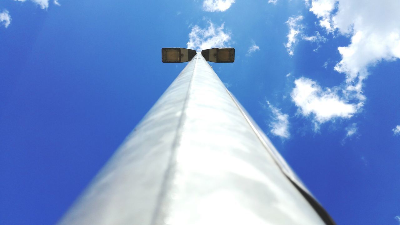 low angle view, blue, sky, built structure, architecture, tall - high, sunlight, day, no people, cloud, outdoors, tower, white color, cloud - sky, high section, part of, building exterior, pole, tall, cross