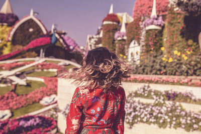 Rear view of woman standing by flowering tree