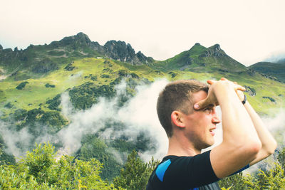 Close-up of man looking away against mountains during foggy weather