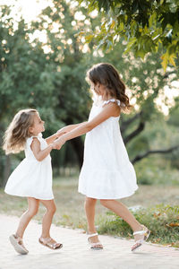 Full length of young woman standing against trees