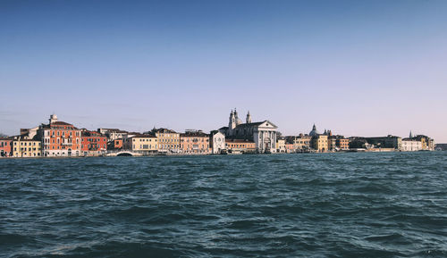 View of buildings by canal against clear sky