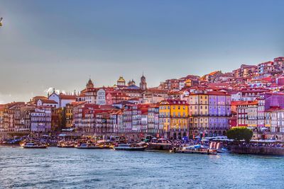 Buildings by river against sky in city