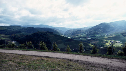 Road amidst field and mountains against sky