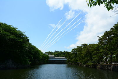 Scenic view of vapor trails over lake against sky