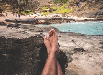 Low section of man legs on rock at beach