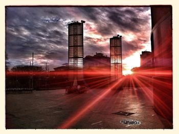 Silhouette of buildings against cloudy sky at sunset