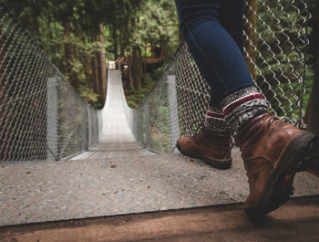 Low section of woman walking on footbridge