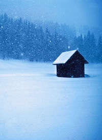 House on snow covered field by building