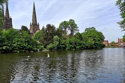 Scenic view of river by buildings against sky