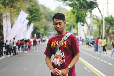 Portrait of young man standing on road in city