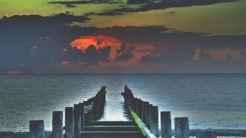 Pier in sea at sunset