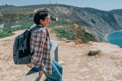 Adult woman backpack went hiking in mountains near the sea in summer, spring sunny day for health