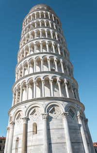 Low angle view of the leaning tower of pisa with moon on the background