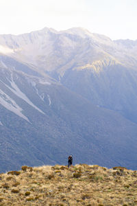 A couple embracing in front of mountains seen from the avalanche peak trail in arthur's pass