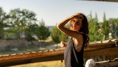 Portrait of young woman standing against railing