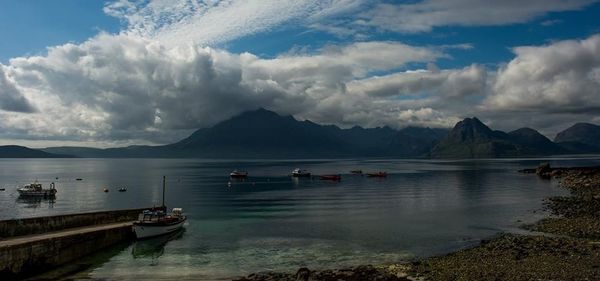 Boats in sea against cloudy sky