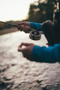 Detail of fly-fisherman stripping line while fishing in twilight