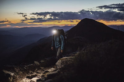 Hiker on mountaintop at dusk with headlamp, bigelow, maine