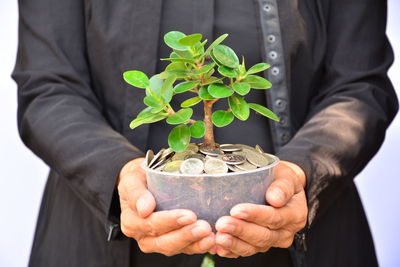 Midsection of man holding seedling in coins