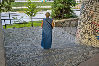 Rear view of woman walking on staircase outdoors